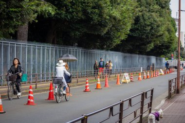 Tokyo, Japonya, 31 Ekim 2023: Bisikletçiler şehirde belirlenmiş bisiklet yolu boyunca gidiyorlar