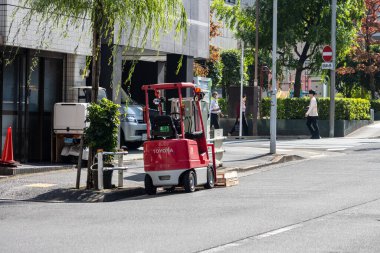 Tokyo, Japonya, 1 Kasım 2023: Forklift arka planda yaya olan bir şehir caddesinde çalışıyor