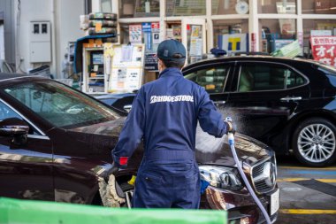 Tokyo, Japonya, 1 Kasım 2023: Bridgestone servis personeli bir benzin istasyonunda araba temizliyor