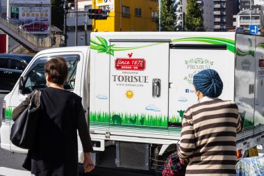 Tokyo, Japonya, 1 Kasım 2023: Madalyalı bir kargo kamyonunun önünden geçen insanlar