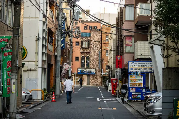 Tokyo, Japonya, 1 Kasım 2023: Dar bir sokakta asılı fenerlerle yürüyen adam