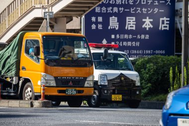 Tokyo, Japonya, 1 Kasım 2023: Sarı teslimat kamyonu arka planda Japonca işaretlerle yol kenarına park edildi