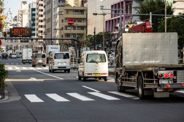 Tokyo, Japonya, 1 Kasım 2023: Yaya geçidine sahip bir şehir yolunda kamyon ve arabalarla trafik sahnesi