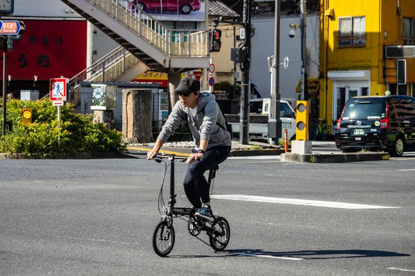 Tokyo, Japonya, 1 Kasım 2023: Kentsel caddede katlanan bisiklete binen adam