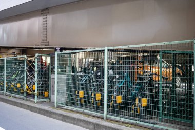 Tokyo, Japonya, 2 Kasım 2023: Bir tren istasyonunun yakınındaki çitli bir alanda park edilmiş bisikletler