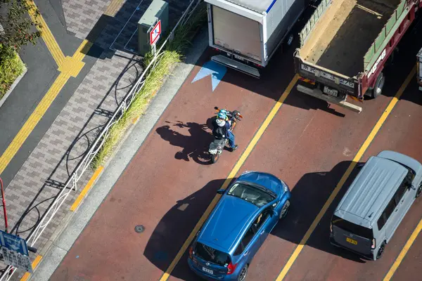 Tokyo, Japonya, 2 Kasım 2023: Şehir trafiğinde yol alan bir motosikletin hava görüntüsü
