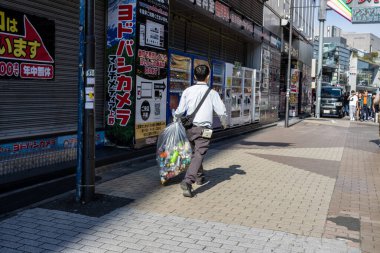 Tokyo, Japonya, 2 Kasım 2023: Reklam panolarının önünden geçen adam