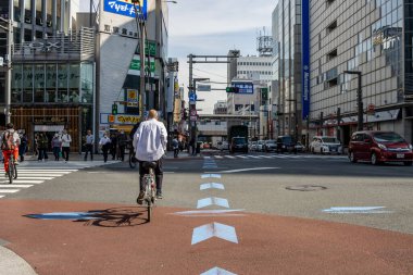 Tokyo, Japonya, 2 Kasım 2023: Yayalar ve trafik olan bir şehir caddesinde bisikletçi