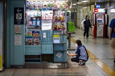 Tokyo, Japonya, 2 Kasım 2023: Metro istasyonunun önünde çömelmiş kişi