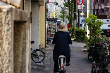 Tokyo, Japonya, 2 Kasım 2023: Tokyo caddesinde bisiklet süren yaşlı kişi