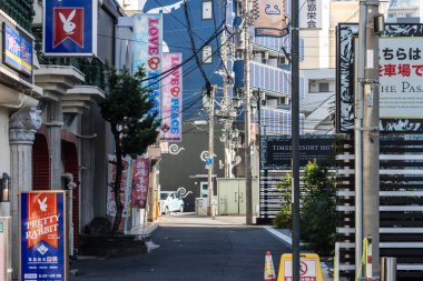 Tokyo, Japonya, 3 Kasım 2023: Değişik mağaza afişleri ve bir park levhası olan sessiz cadde