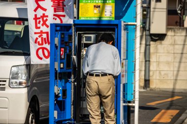 Tokyo, Japonya, 3 Kasım 2023: Sokaktaki bir makineyi tamir eden mühendis