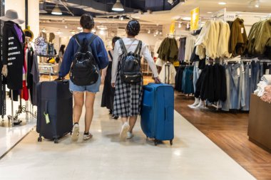 Tokyo, Japonya, 4 Kasım 2023: Moda Perakende Mağazasında iki kişi bavulla alışveriş yapıyor