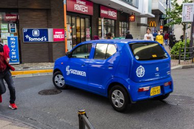 Tokyo, Japonya, 4 Kasım 2023: Blue Suzuken Company Car Driving McDonald 's ve Tomod' s Stores on Busy Street