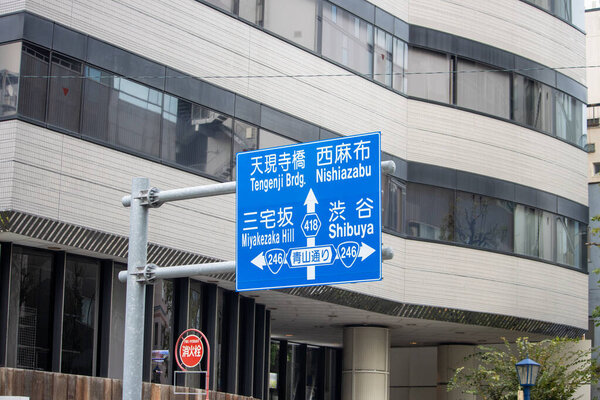 Tokyo, Japan, 4 November 2023: Directional Road Sign with Japanese and English Inscriptions Pointing towards Shibuya and Nishiazabu