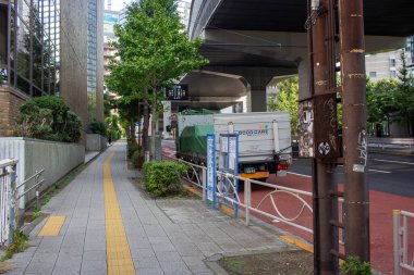 Tokyo, Japonya, 4 Kasım 2023: Başında otoyol ve park halindeki teslimat kamyonu olan şehir caddesi