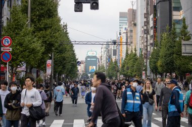 Tokyo, Japonya, 5 Kasım 2023: Meşgul bir caddeden geçen yayalar ve modern reklam panoları