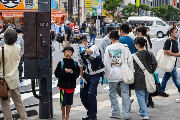 Tokyo, Japonya, 5 Kasım 2023: Polis memuru ve yayalarla sokak sahnesi