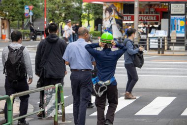Tokyo, Japonya, 6 Kasım 2023: İnşaat işçisi akıllı telefonla sokak hayatını yakalıyor