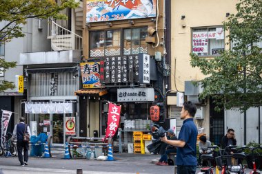 Tokyo, Japan, November 6 2023 : Urban scene with local businesses and pedestrians clipart