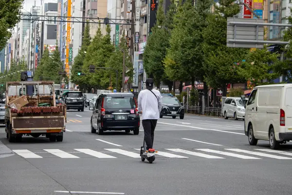 Tokyo, Japonya, 6 Kasım 2023: Urban Caddesi 'nde Elektrikli Scooter kullanan adam