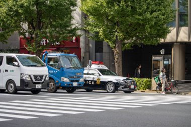 Tokyo, Japonya, 6 Kasım 2023: Polis arabası ve yayaların olduğu şehir caddesi