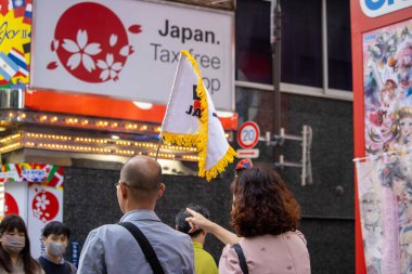 Tokyo, Japan, 6 November 2024: Tourists Pointing at Tax-Free Sign in Busy Shopping Area clipart