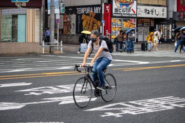Tokyo, Japonya, 6 Kasım 2024: Urban Setting 'de Karşıdan karşıya geçen bisikletçi