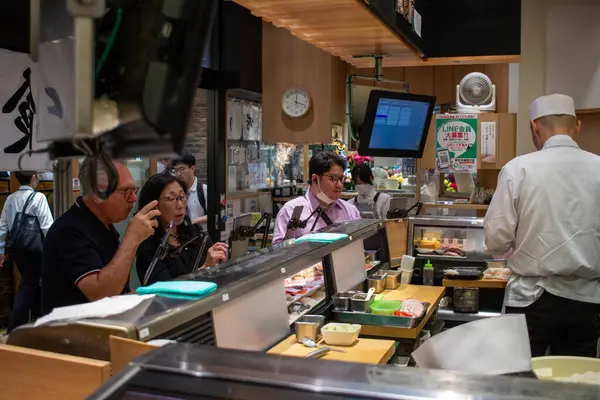 Tokyo, Japonya, 6 Kasım 2024: Aşçılar ve Müşterilerle Yoğun Suşi Restoranı