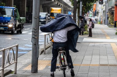 Tokyo, Japonya, 7 Kasım 2024: İşadamı Yağmur Altında Bisiklet Sürüyor