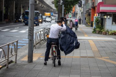 Tokyo, Japonya, 7 Kasım 2024: Bisikleti Yağmurda Kaplayan Adam