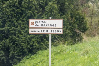 France, 07 April 2024: Directional signpost to Grottes de Maxange amid lush greenery clipart