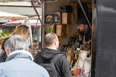 France, 30 March 2024: Vendor Engaging with Customers at Outdoor Market Stall clipart