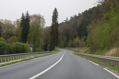 Fransa, 07 Nisan 2024: Bereketli yeşil ormanların içinden geçen sakin köy yolu