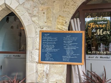 Fransa, 3 Mayıs 2024: Bir Fransız restoranının dışındaki tuhaf bir taş kemer yolunda kara tahta menü sergilendi