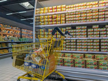 France, 11 April 2024: Grocery shopping cart in front of canned food aisle in supermarket clipart