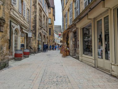 Fransa, 7 Nisan 2024: Eski taş binalar ve yürüyen insanların bulunduğu tarihi bir kasabada büyüleyici dar bir caddenin manzarası.