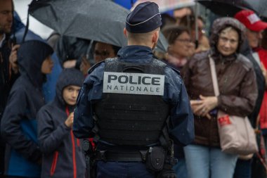 Fransa, 22 Mayıs 2024: Kalabalık yağmur altında duran polis memuru