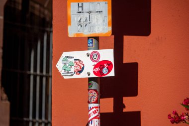 Almanya, 10 Haziran 2024: Turuncu bir duvarın önündeki sokak levhaları