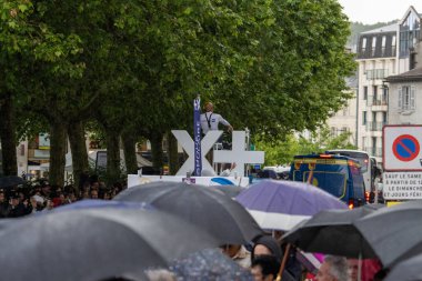 Fransa, 22 Mayıs 2024: Şemsiyeli kalabalık, çapraz sembol ve polis varlığıyla kamuoyu önünde toplandı