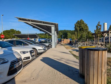 Fransa, 10 Ağustos 2024: Güneş paneli tepe örtüsü altında elektrikli taşıt şarj istasyonları bulunan park yeri