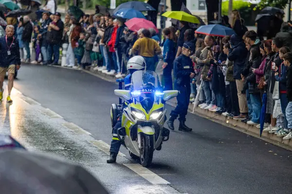 Fransa, 22 Mayıs 2024: Motosikletli polis memuru yağmur altında kalabalığın önünde geçit töreni düzenledi
