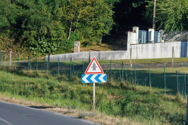 stock image France, 10 August 2024: Road sign indicating sharp left turn with trees ahead