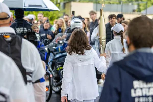 stock image France, 22 May 2024: Torchbearer carrying Olympic torch surrounded by crowd during relay event