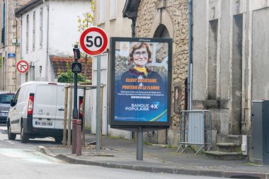 Fransa, 19 Mayıs 2024: Hız sınırı levhası yakınlarındaki küçük bir kasaba sokağında reklam panosu