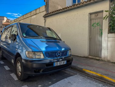 Fransa, 16 Ağustos 2024: Mavi Mercedes-Benz minibüsü bir iskan binasının yanındaki sokağa park edildi