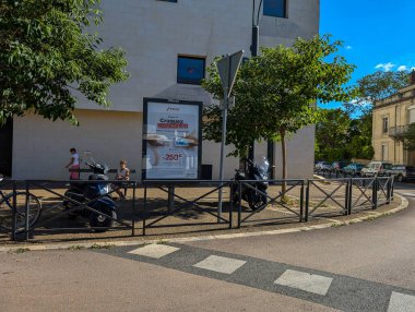 Fransa, 16 Ağustos 2024: Açık hava reklam panosu ve şehir caddesinde park edilmiş motosikletler