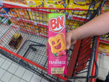 Fransa, 12 Ağustos 2024: Süpermarket alışveriş arabasında BN ahududu bisküvileri tutan kişi