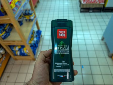 Fransa, 13 Ağustos 2024: Petrol Hahn şampuan şişesini bir mağaza koridorunda tutan kişi