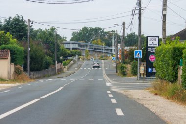 Fransa, 15 Ağustos 2024: Trafik işaretleri ve yeşillikleri olan boş banliyö yolu